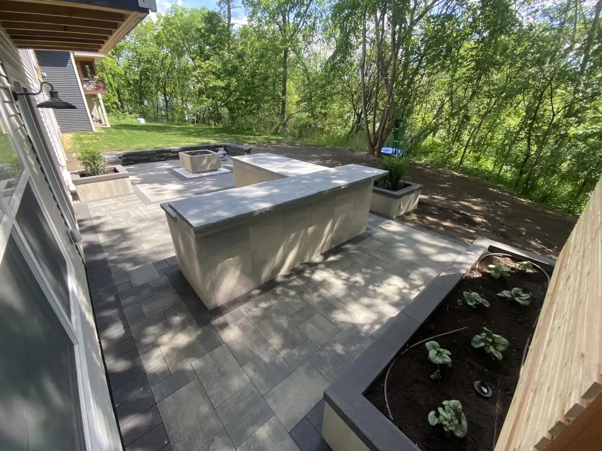 Estate tier full outdoor living space with kitchen island, fire feature, and integrated planters — $50-75K Minnesota landscape project