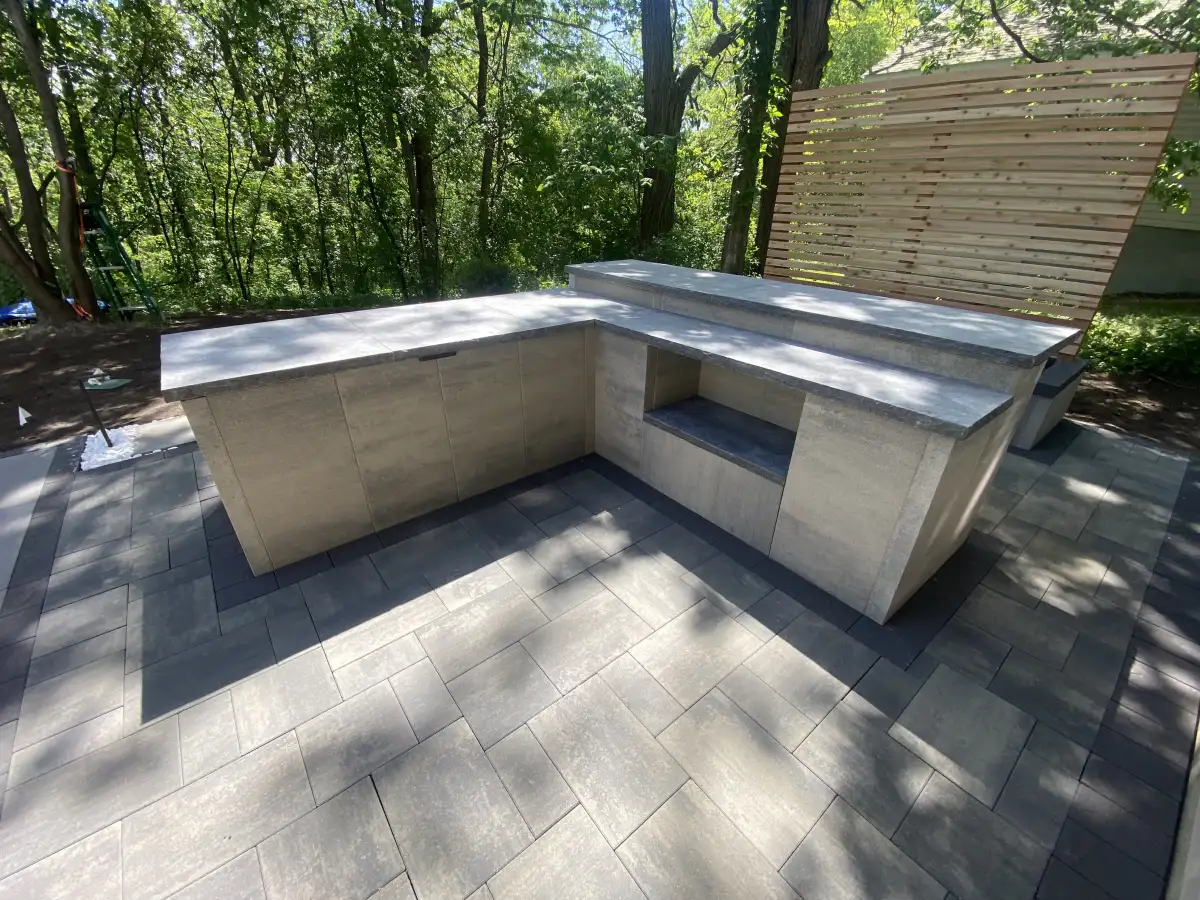 Estate tier L-shaped outdoor kitchen with Belgard pavers and cedar screening in Minnesota