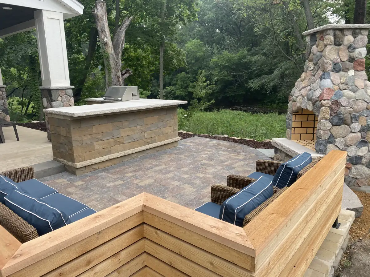 Legacy tier outdoor kitchen with stone fireplace and built-in seating — $150K+ project by Landscape Charlie