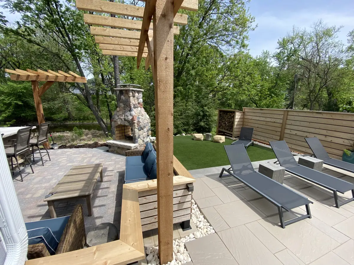 Legacy tier pergola with stone fireplace, multiple outdoor rooms, and turf lounge area