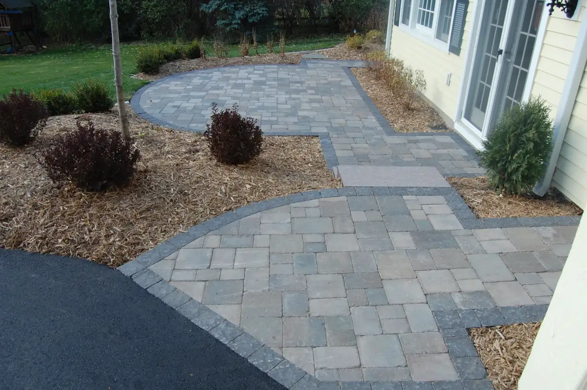 Signature tier paver walkway with curved path and foundation plantings — $10-20K project by Landscape Charlie