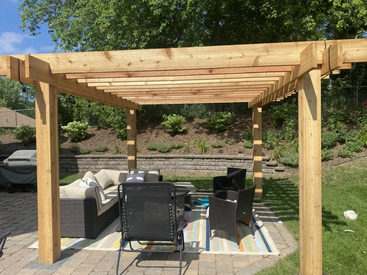 Freestanding pergola defining outdoor dining space on paver patio