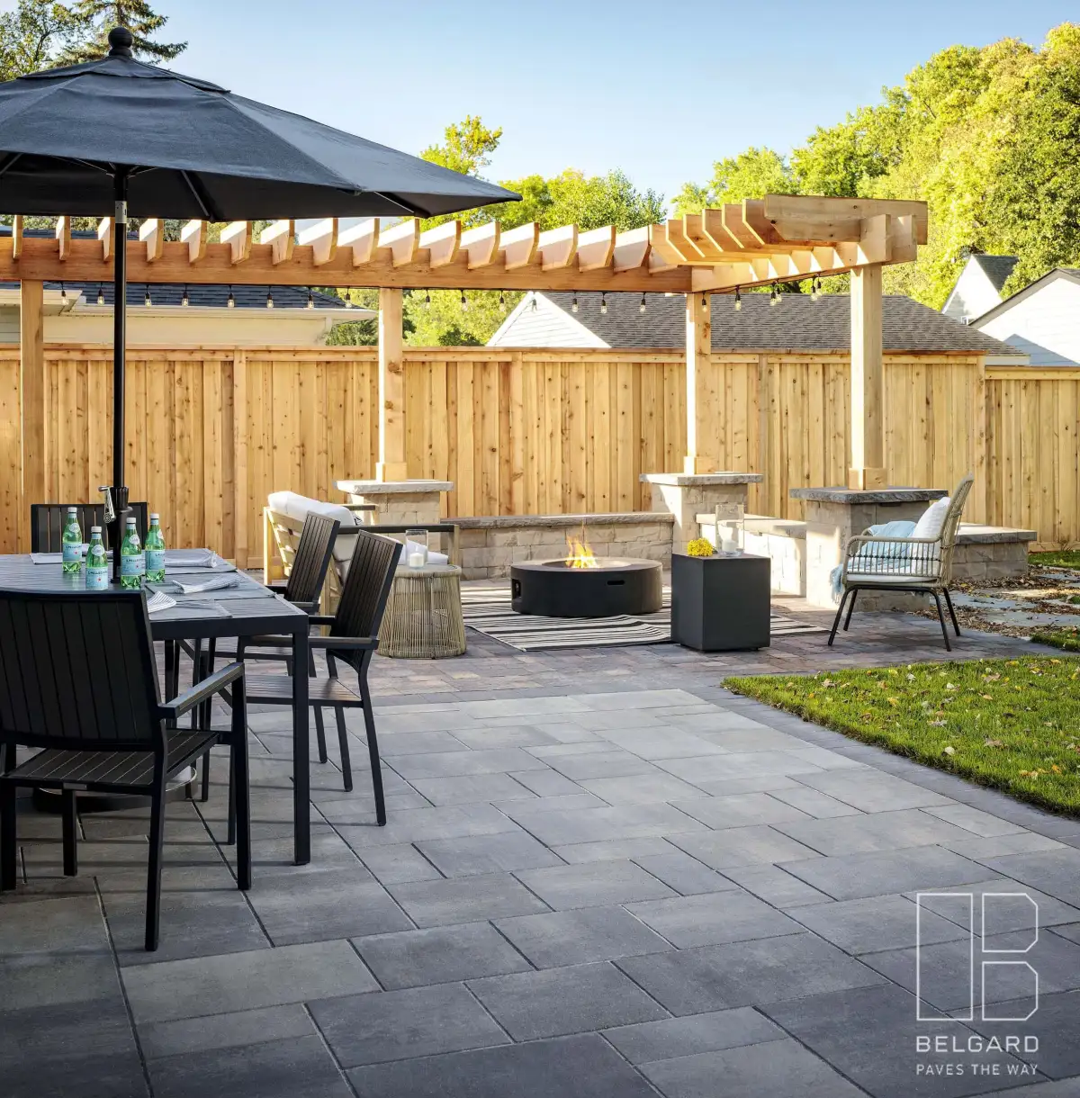 Paver patio with a dining table, umbrella, wood pergola and lounge seating