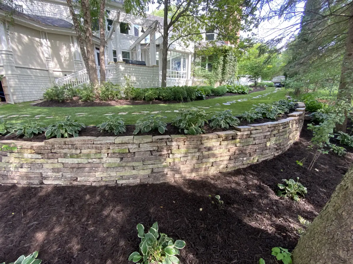 Curved stone retaining wall surrounding a landscaped Minnesota yard